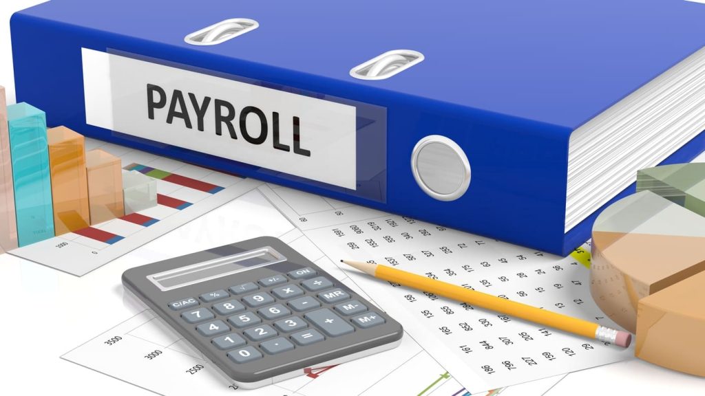 Carpeta de payroll junto a una calculadora y gráficos financieros que representan la gestión de nómina, los reportes y depósitos de impuestos de empleados.